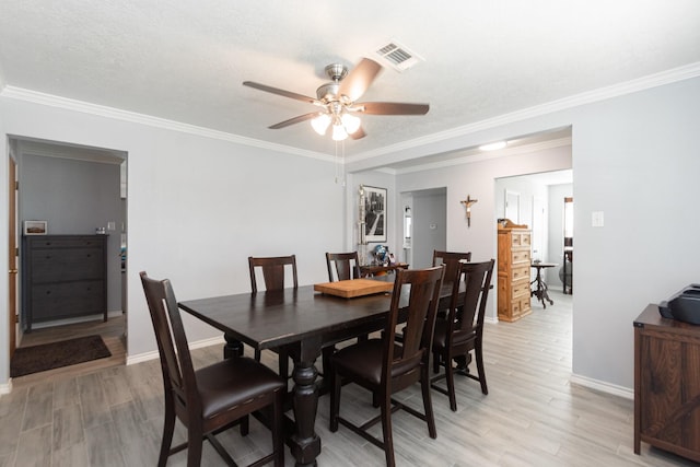 dining space featuring baseboards, visible vents, ceiling fan, and light wood-style floors