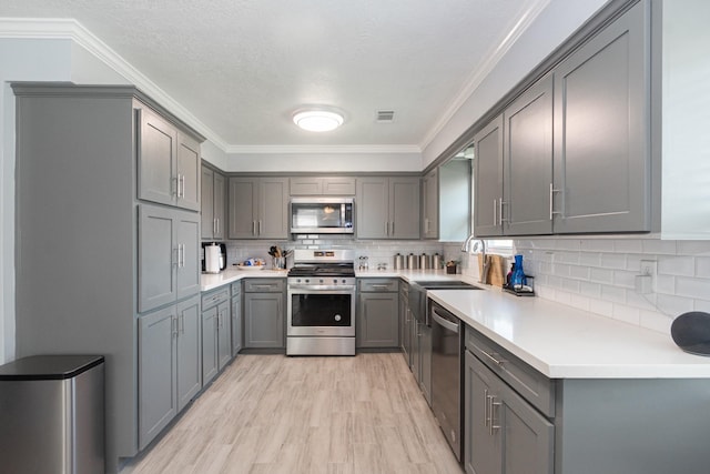 kitchen featuring crown molding, appliances with stainless steel finishes, visible vents, gray cabinetry, and light wood-type flooring