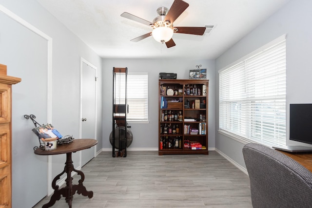 office area featuring ceiling fan, light wood finished floors, and baseboards