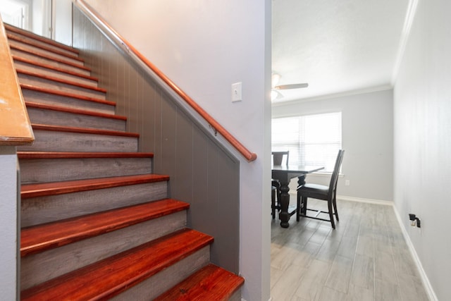 staircase with baseboards, wood finished floors, a ceiling fan, and crown molding
