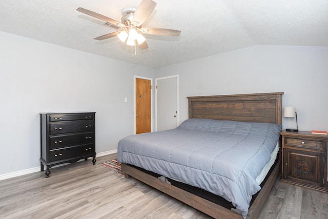 bedroom with lofted ceiling, a textured ceiling, baseboards, wood finished floors, and a ceiling fan