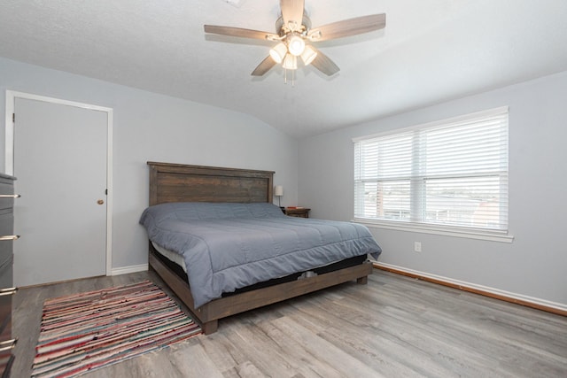 bedroom featuring baseboards, wood finished floors, ceiling fan, and vaulted ceiling