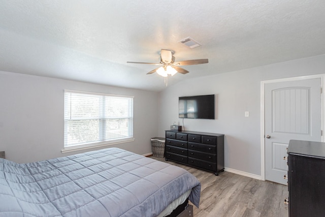 bedroom with a ceiling fan, visible vents, wood finished floors, and baseboards