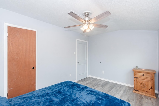 unfurnished bedroom with lofted ceiling, a textured ceiling, wood finished floors, and baseboards
