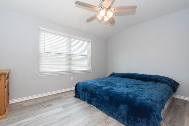 bedroom featuring a ceiling fan, vaulted ceiling, wood finished floors, and baseboards