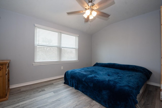 bedroom featuring wood finished floors, a ceiling fan, vaulted ceiling, and baseboards