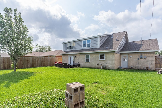 back of property with a lawn, roof with shingles, a fenced backyard, and brick siding