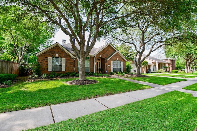 view of front facade with fence, a front lawn, and brick siding