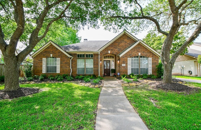ranch-style home featuring fence, roof with shingles, a front yard, and brick siding