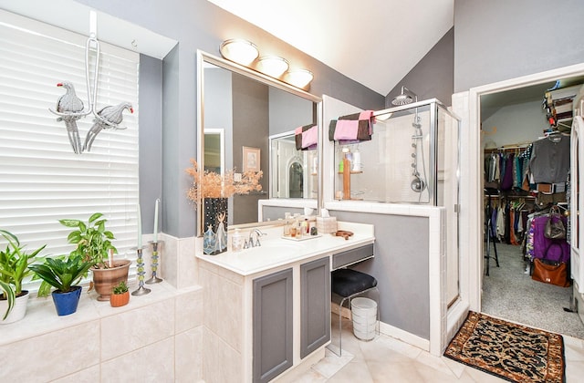 bathroom with a walk in closet, a stall shower, lofted ceiling, and vanity