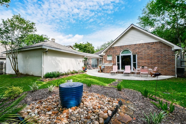 back of property with a patio area, a yard, and brick siding