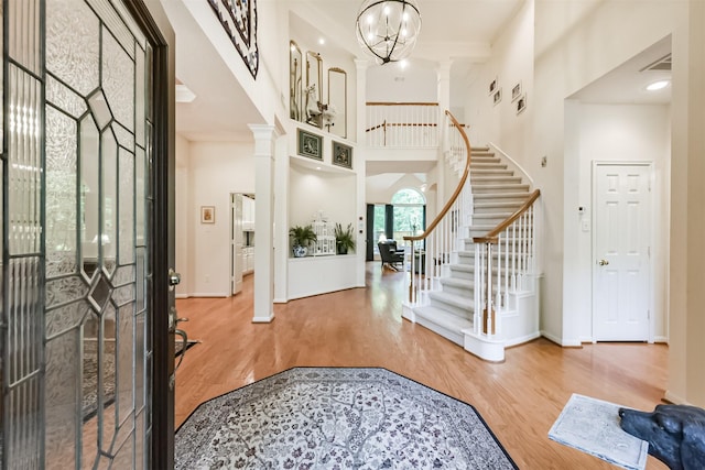 entryway featuring stairs, decorative columns, wood finished floors, and a towering ceiling