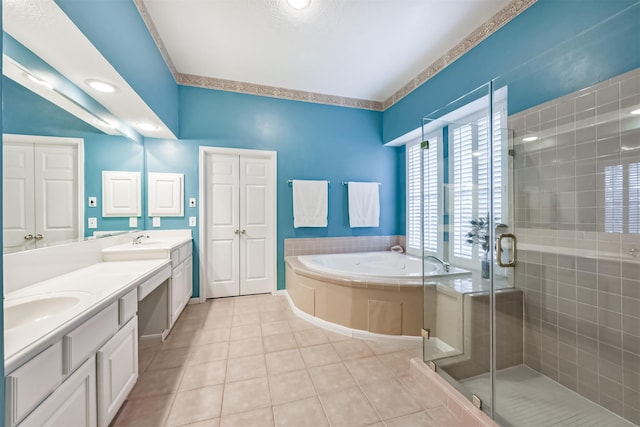 bathroom featuring a garden tub, double vanity, tile patterned floors, a shower stall, and a sink