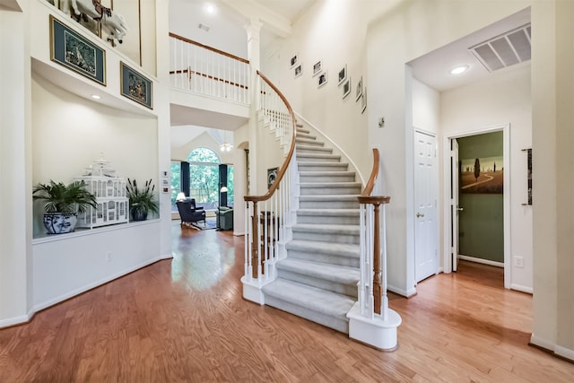 stairs with baseboards, a high ceiling, visible vents, and wood finished floors
