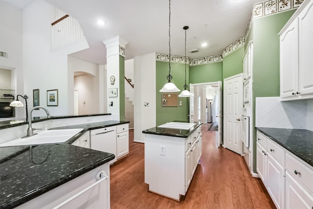 kitchen featuring a kitchen island, a sink, wood finished floors, and white appliances