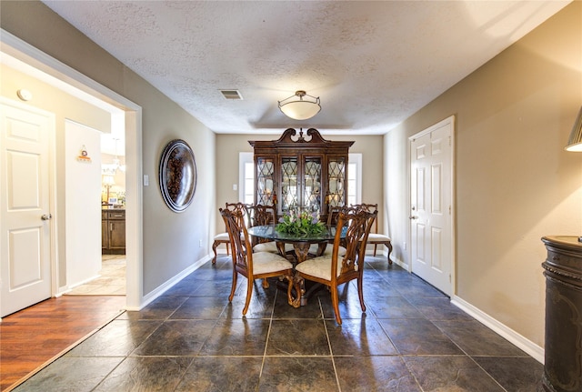 dining space with baseboards, visible vents, and a textured ceiling