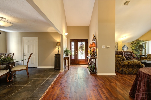 foyer entrance featuring visible vents, baseboards, and dark wood finished floors
