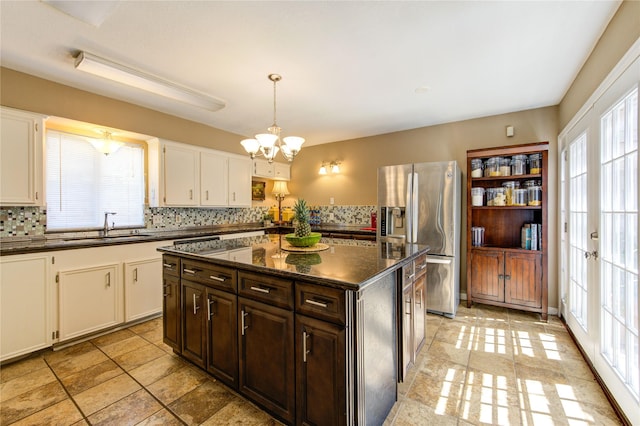 kitchen featuring a chandelier, stainless steel fridge with ice dispenser, backsplash, a sink, and white cabinetry