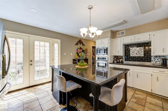 kitchen featuring appliances with stainless steel finishes, visible vents, french doors, and decorative backsplash