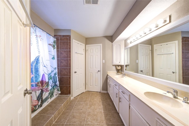 full bathroom with a sink, tiled shower, and visible vents
