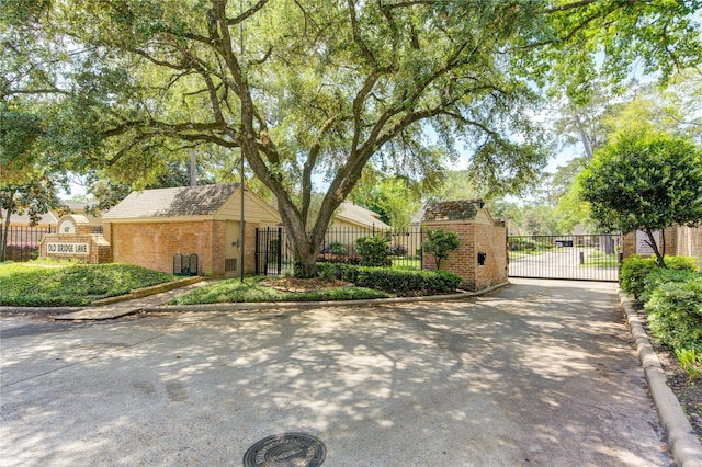 exterior space with a gate, brick siding, and fence
