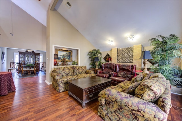 living area with baseboards, visible vents, wood finished floors, and high vaulted ceiling