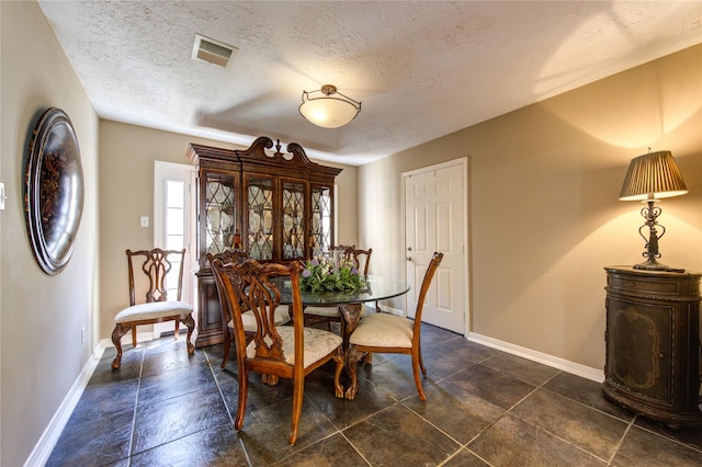dining space with baseboards, visible vents, and a textured ceiling