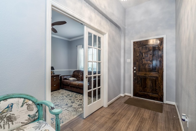 foyer with crown molding, baseboards, and wood finished floors