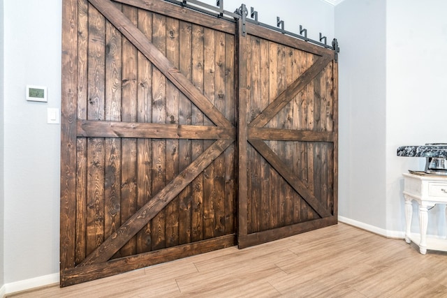 room details featuring baseboards, a barn door, and wood finished floors