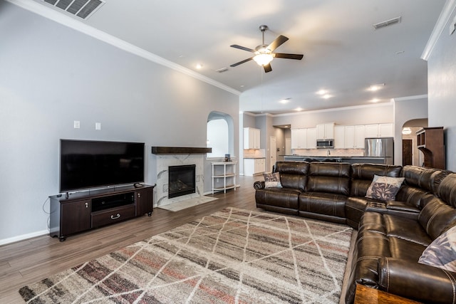 living room featuring crown molding, arched walkways, a ceiling fan, and visible vents