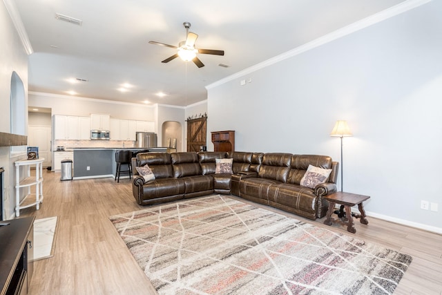 living area featuring arched walkways, ceiling fan, ornamental molding, and light wood-type flooring