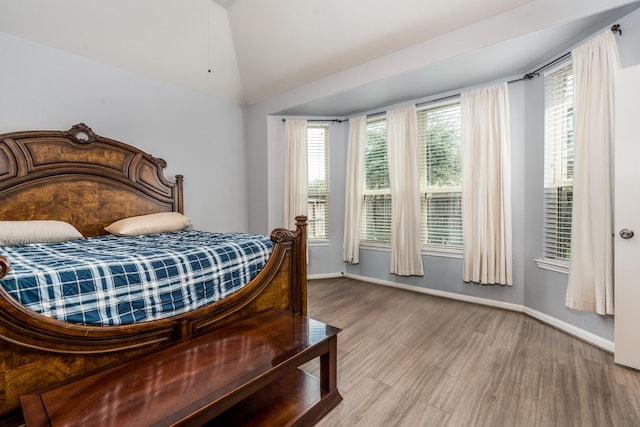 bedroom with baseboards, wood finished floors, and vaulted ceiling