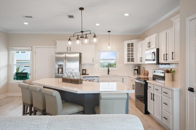 978 Sue Dr, Crystal Beach, TX 77650 - kitchen featuring light wood finished floors, a sink, a kitchen breakfast bar, a kitchen island, and appliances with stainless steel finishes