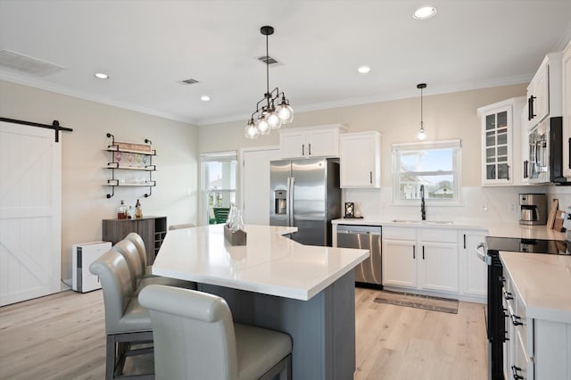978 Sue Dr, Crystal Beach, TX 77650 - kitchen with a barn door, stainless steel appliances, light wood finished floors, a sink, and visible vents