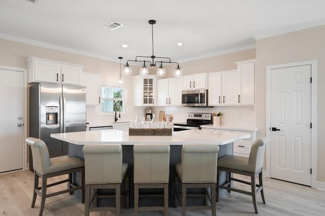 978 Sue Dr, Crystal Beach, TX 77650 - kitchen with white cabinetry, visible vents, stainless steel appliances, and a kitchen island