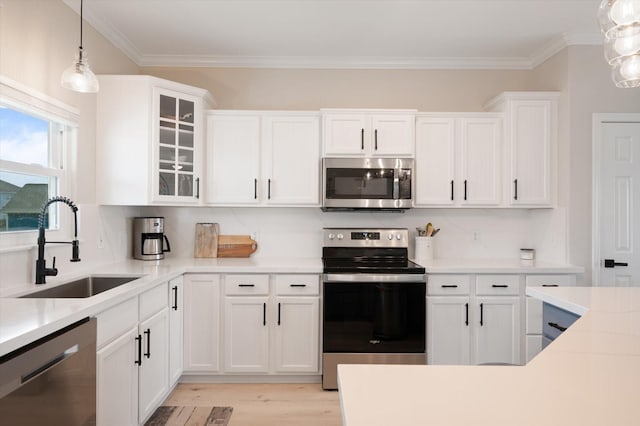 978 Sue Dr, Crystal Beach, TX 77650 - kitchen with a sink, stainless steel appliances, light wood-style floors, crown molding, and white cabinets