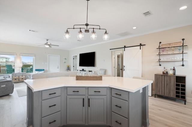 978 Sue Dr, Crystal Beach, TX 77650 - kitchen featuring visible vents, light wood-style floors, a barn door, open floor plan, and gray cabinets