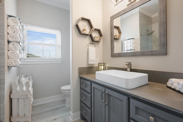 978 Sue Dr, Crystal Beach, TX 77650 - bathroom featuring wood finished floors, toilet, vanity, baseboards, and crown molding