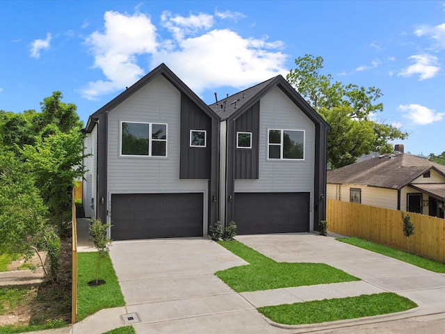 view of front of property featuring driveway, a garage, board and batten siding, and fence