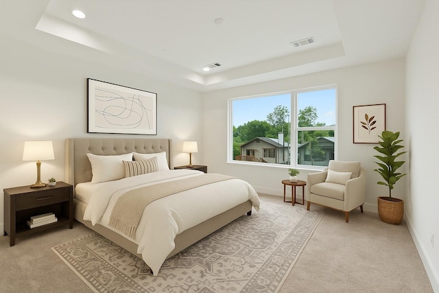 bedroom with visible vents, baseboards, a tray ceiling, and light carpet