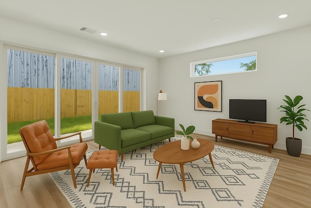 living area with baseboards, visible vents, light wood-type flooring, and recessed lighting