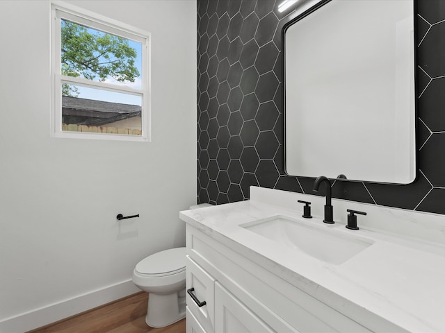 bathroom with baseboards, wood finished floors, toilet, and vanity