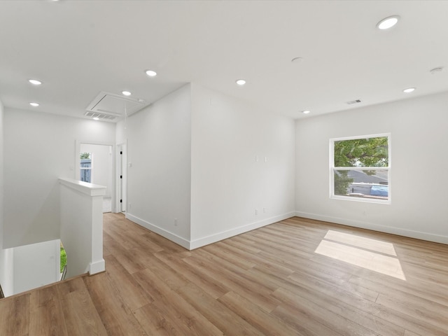 empty room with attic access, recessed lighting, light wood finished floors, and baseboards