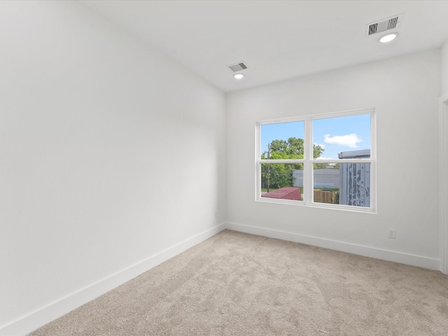 unfurnished room with baseboards, visible vents, and light colored carpet