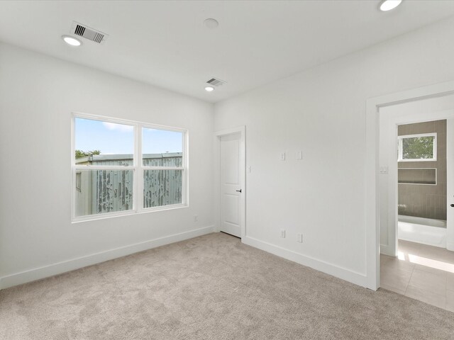 unfurnished room with visible vents, a healthy amount of sunlight, baseboards, and carpet floors