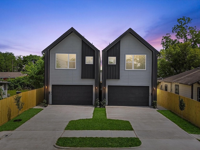 view of front of house with fence, concrete driveway, board and batten siding, and a garage