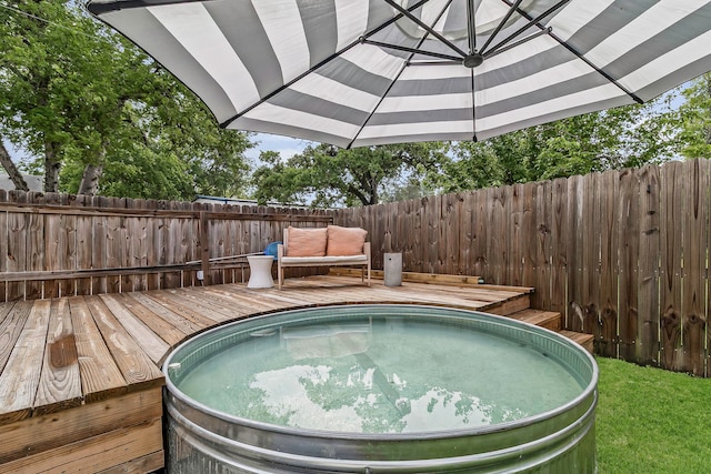 view of swimming pool featuring a deck, a fenced backyard, and a jacuzzi