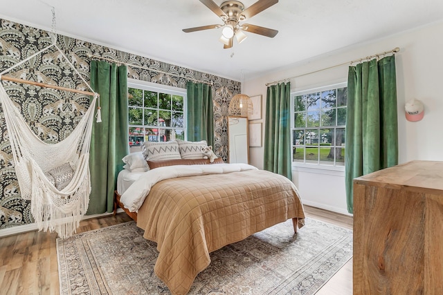 bedroom with wood finished floors, a ceiling fan, and multiple windows