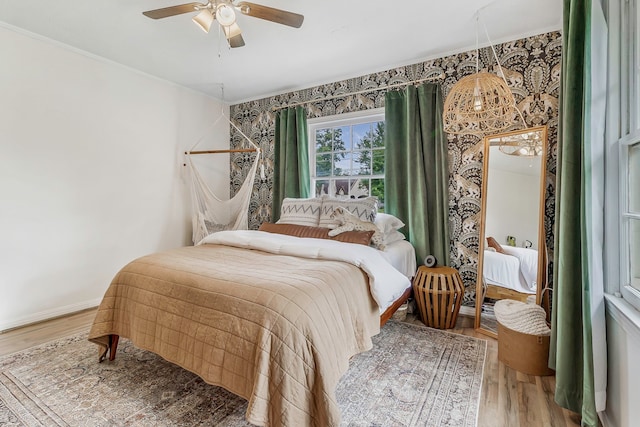 bedroom featuring ornamental molding, light wood finished floors, ceiling fan, and baseboards