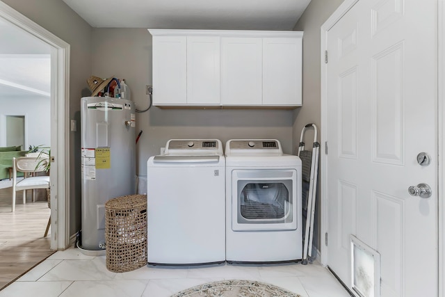 washroom with cabinet space, electric water heater, and independent washer and dryer